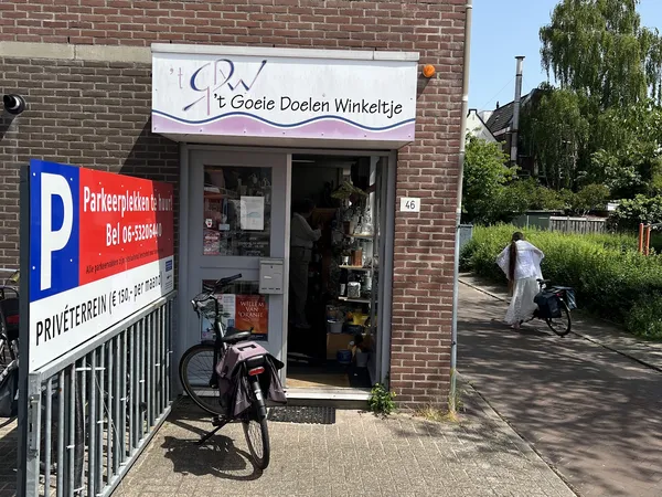 Gevel van kringloopwinkel 't Goeie Doelen Winkeltje aan Yperstraat, met winkelnaambord, deur en fietsen ervoor