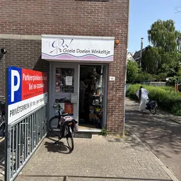 Gevel van kringloopwinkel 't Goeie Doelen Winkeltje aan Yperstraat, met winkelnaambord, deur en fietsen ervoor