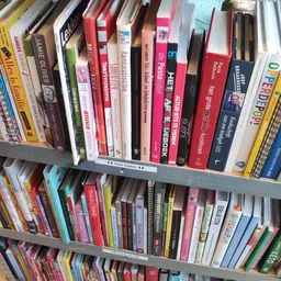 Boekenrekken met tweedehands boeken in verschillende genres en kleuren in een kringloopwinkel
