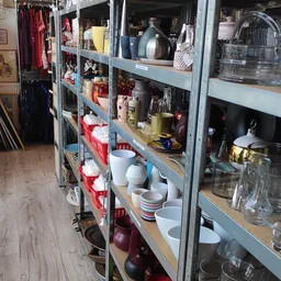 Stellingen met huishoudelijke artikelen: serviesgoed, kopjes, potten en keukenspullen