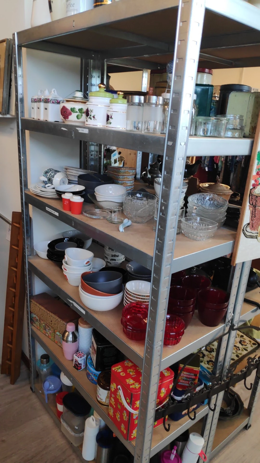 Metalen stellingkast met serviesgoed, glazen schalen en keukengerei netjes uitgestald