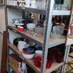 Metalen stellingkast met serviesgoed, glazen schalen en keukengerei netjes uitgestald