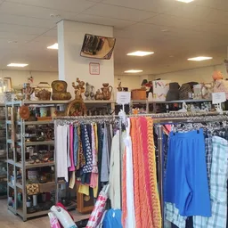 Winkelvloer met kledingrekken, stellingen met spullen en decoraties aan de muur