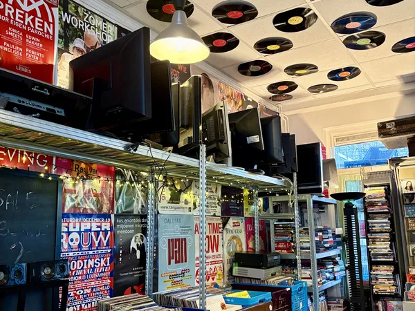 Winkelbinnenkant met stellingen, vinyl records aan plafond, en diverse tweedehands spullen op display