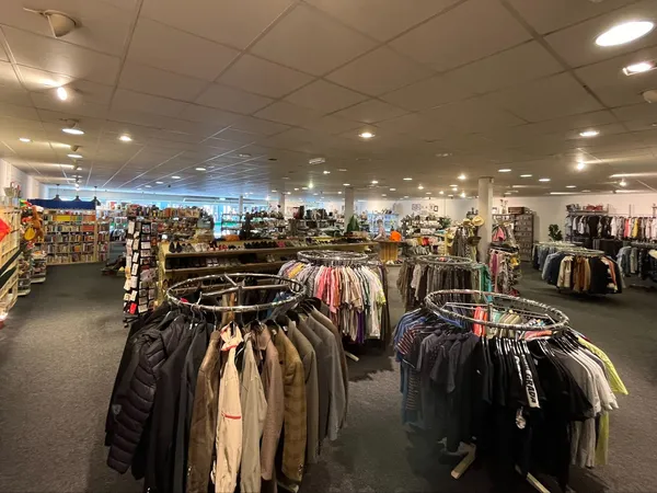 Winkelvloer met kledingrekken en stellingen vol tweedehands kleding in verschillende kleuren