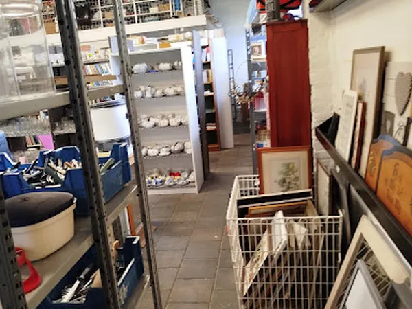 Winkelinterieur met stellingen, uitgestalde artikelen, frames tegen de muur en winkelwagens in het middenpad