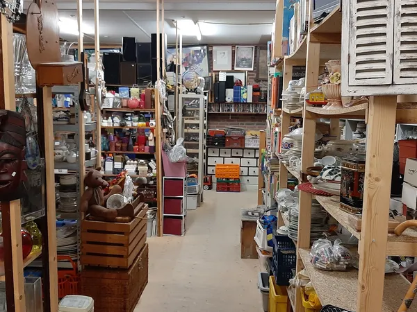 Winkelinterieur met houten stellingen vol diverse tweedehands spullen, dozen en huishoudartikelen