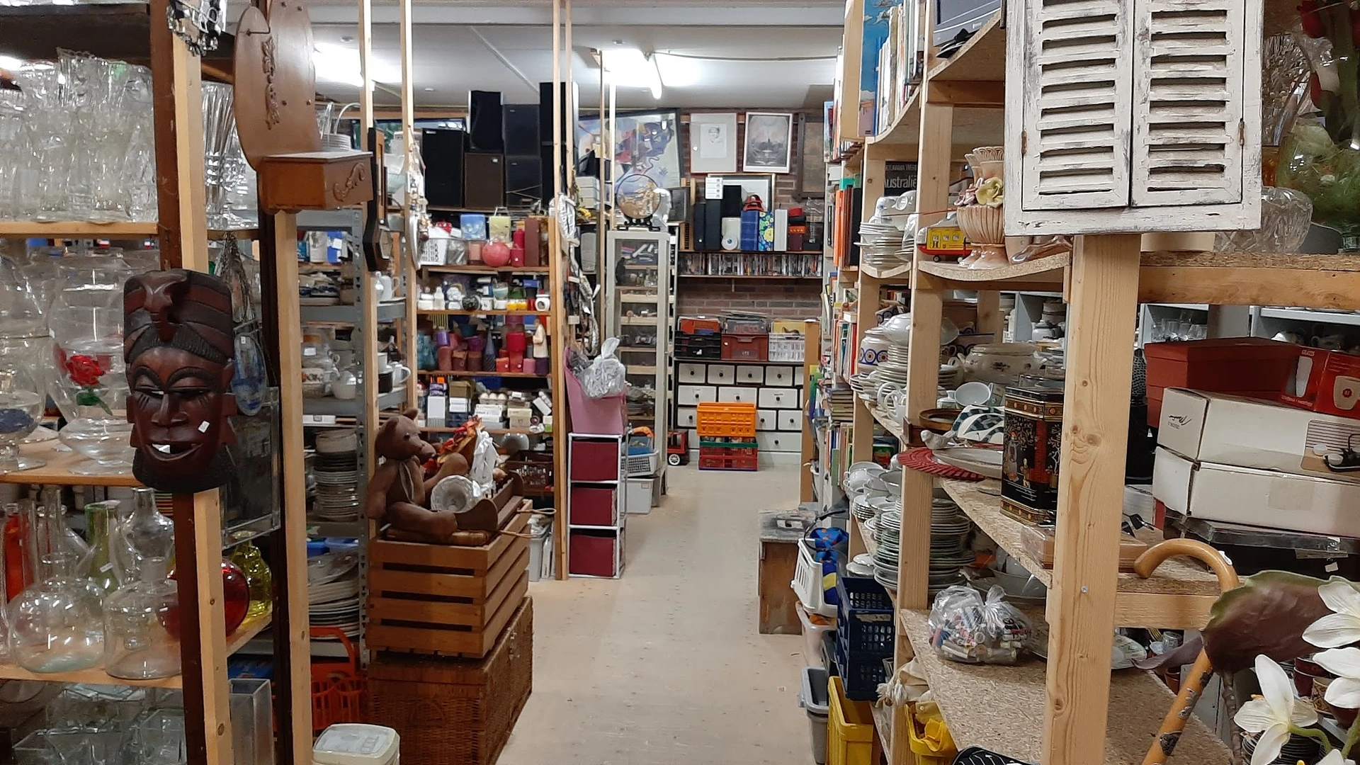 Winkelinterieur met houten stellingen vol diverse tweedehands spullen, dozen en huishoudartikelen