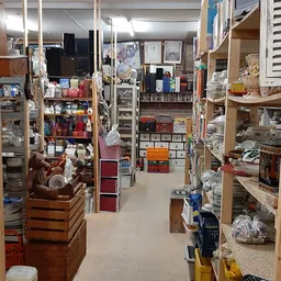 Winkelinterieur met houten stellingen vol diverse tweedehands spullen, dozen en huishoudartikelen