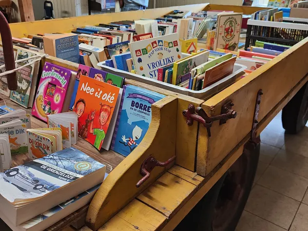 Houten kar vol met tweedehands boeken in verschillende talen en formaten
