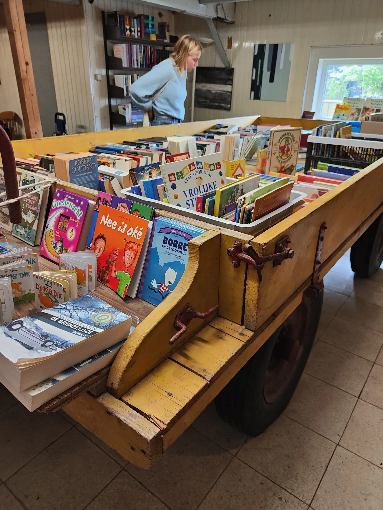 Houten kar vol met tweedehands boeken in verschillende talen en formaten