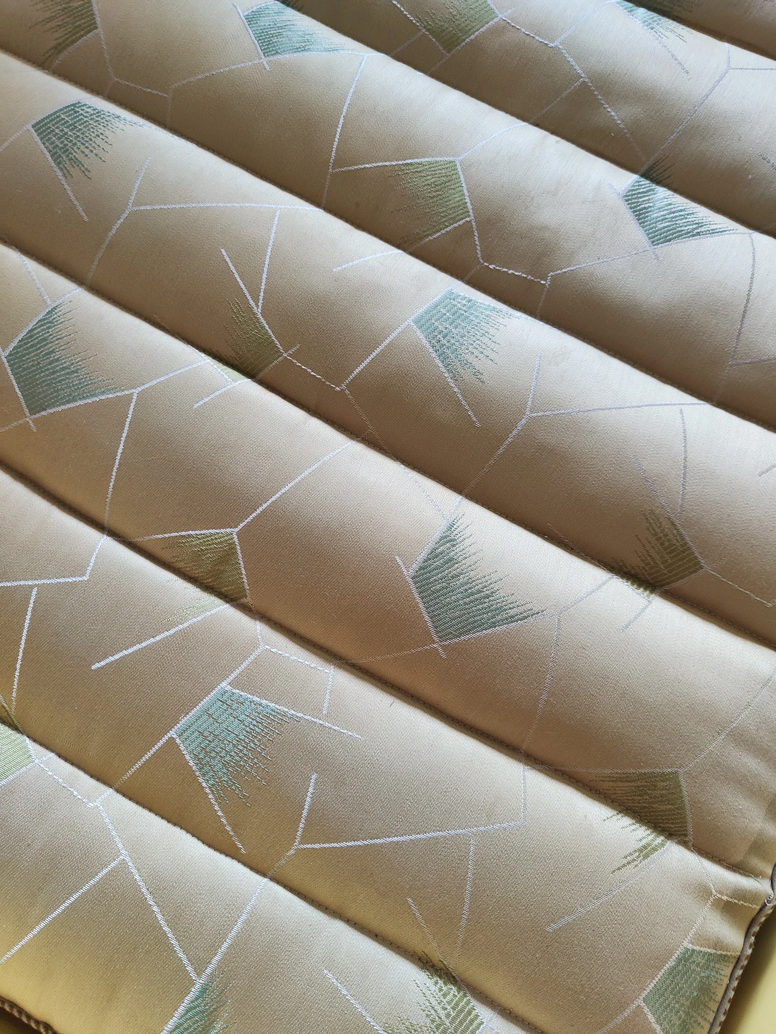 Opgerold behang of textiel met geometrisch patroon in beige, groen en wit