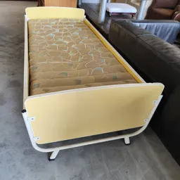Geel kinderbedje met wit frame en matras met patroon