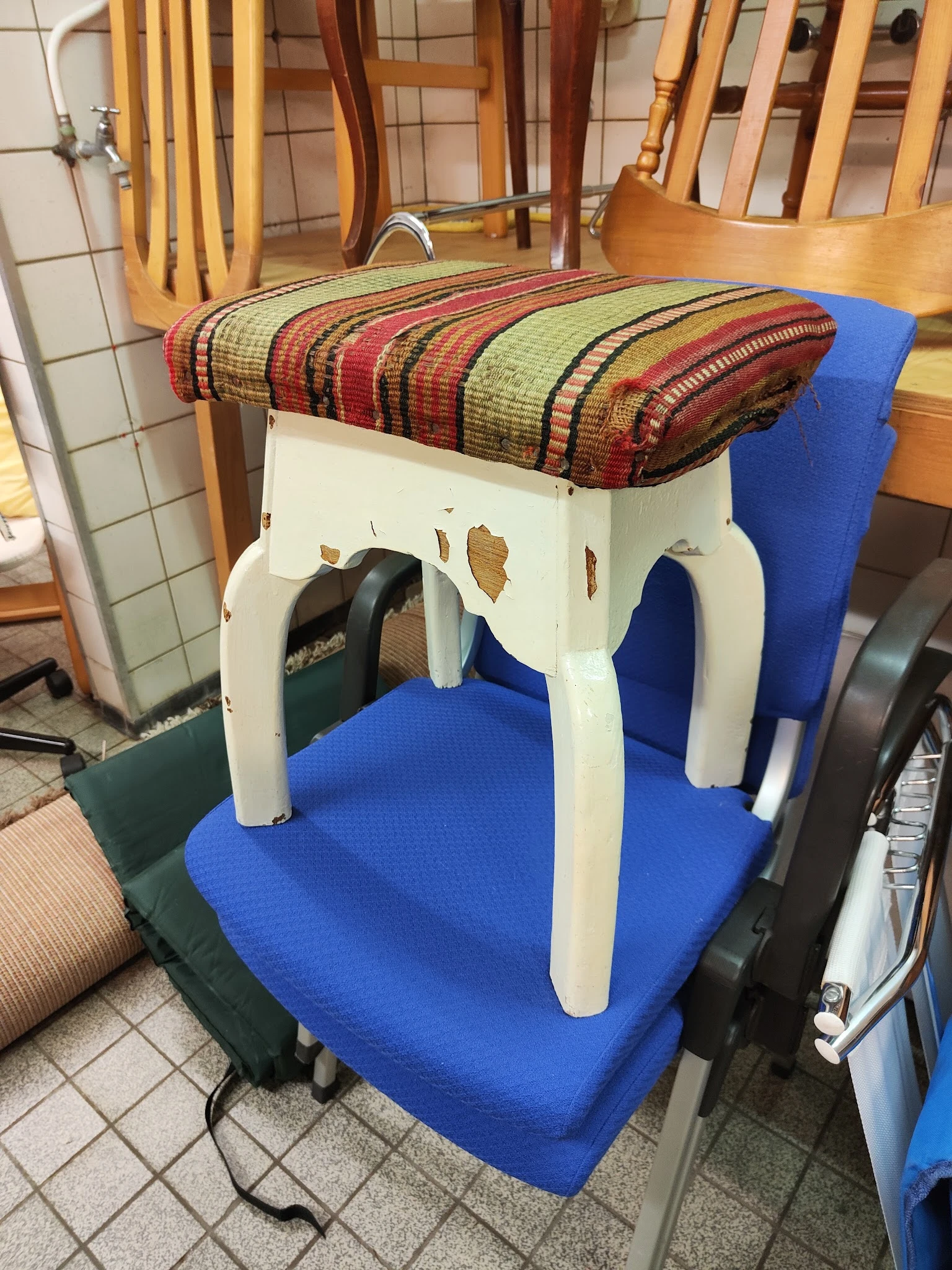 Witte kruk of tafel met gestreepte stofkussenzitting, staand op blauwe ondergrond