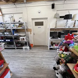 Winkelvloer met stellingen vol tweedehands spullen, meubels, lampen en textiel
