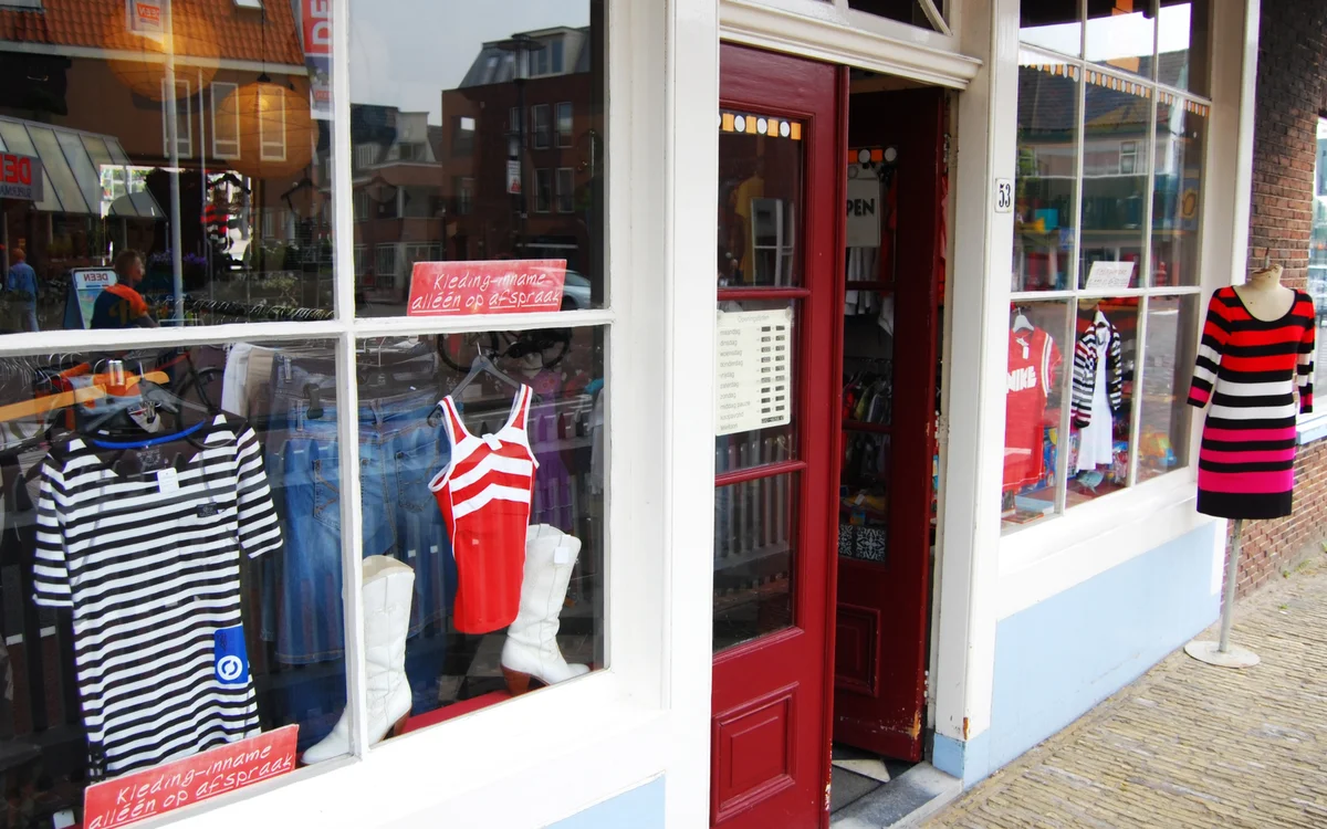Winkelpui met rode deur en etalageruiten met tweedehands kleding in rood en zwart