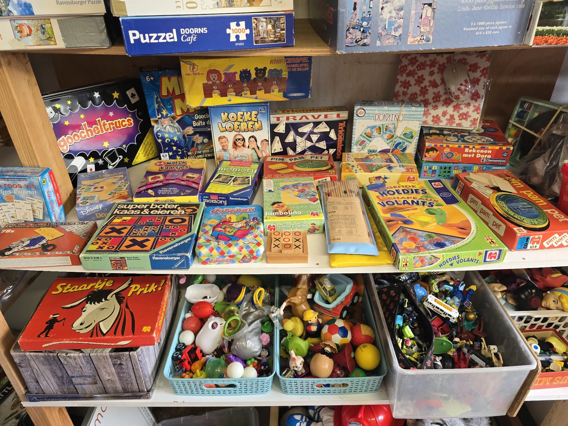 Planken vol speelgoed, bordspellen, puzzels en verzamelobjecten in een kringloopwinkel
