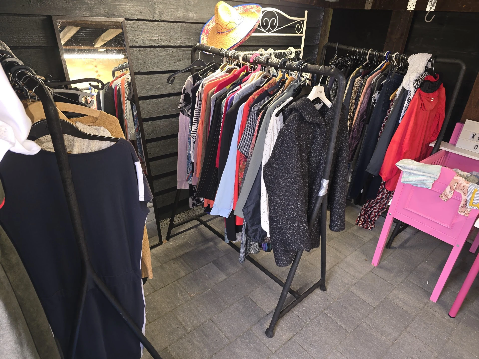 Rekken met tweedehands kleding in verschillende kleuren en stijlen