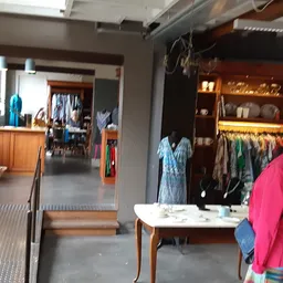 Winkelinterieur met kledingrekken, houten tafels en goederen uitgestald