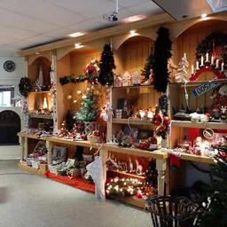 Kerstafdeling in kringloopwinkel met houten stellingen vol decoraties, verlichtingen en kerstartikelen