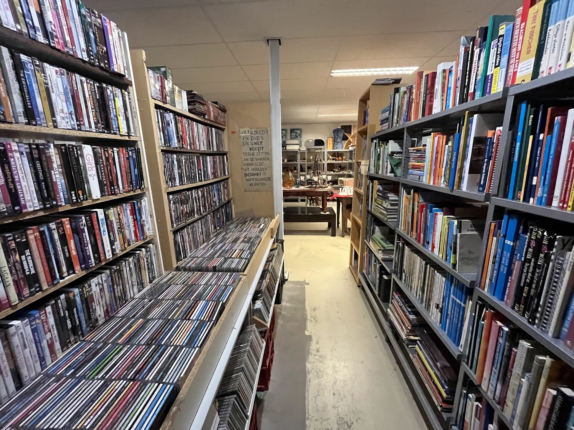 Gangpad tussen rekken vol dvd's en blu-rays in een kringloopwinkel