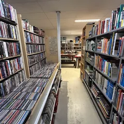 Gangpad tussen rekken vol dvd's en blu-rays in een kringloopwinkel