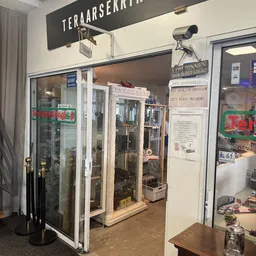 Winkelinterieur met glazen vitrinekasten en stellingen met spullen, witte wanden en waarschuwingsborden
