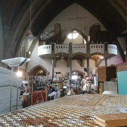 Ruim interieur van kringloopwinkel met hooge plafonds, galerijen en diverse tweedehandsartikelen uitgestald
