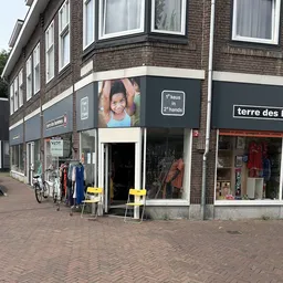 Winkelpui van kringloopwinkel aan straat met etalage, ingang en tweedehands kleding zichtbaar