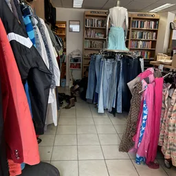 Rekken met tweedehands kleding in verschillende kleuren en maten in de winkel