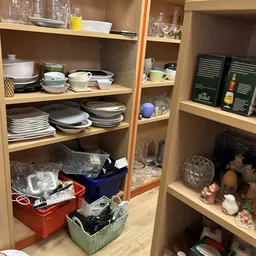 Open kasten met serviesgoed, glazen, boeken en huishoudelijke artikelen