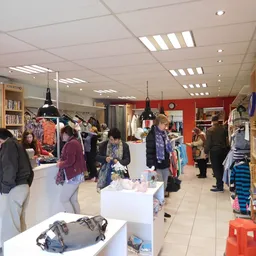 Winkelvloer met klanten, witte display-tafels, houten kasten, rode wand en hangende lampen