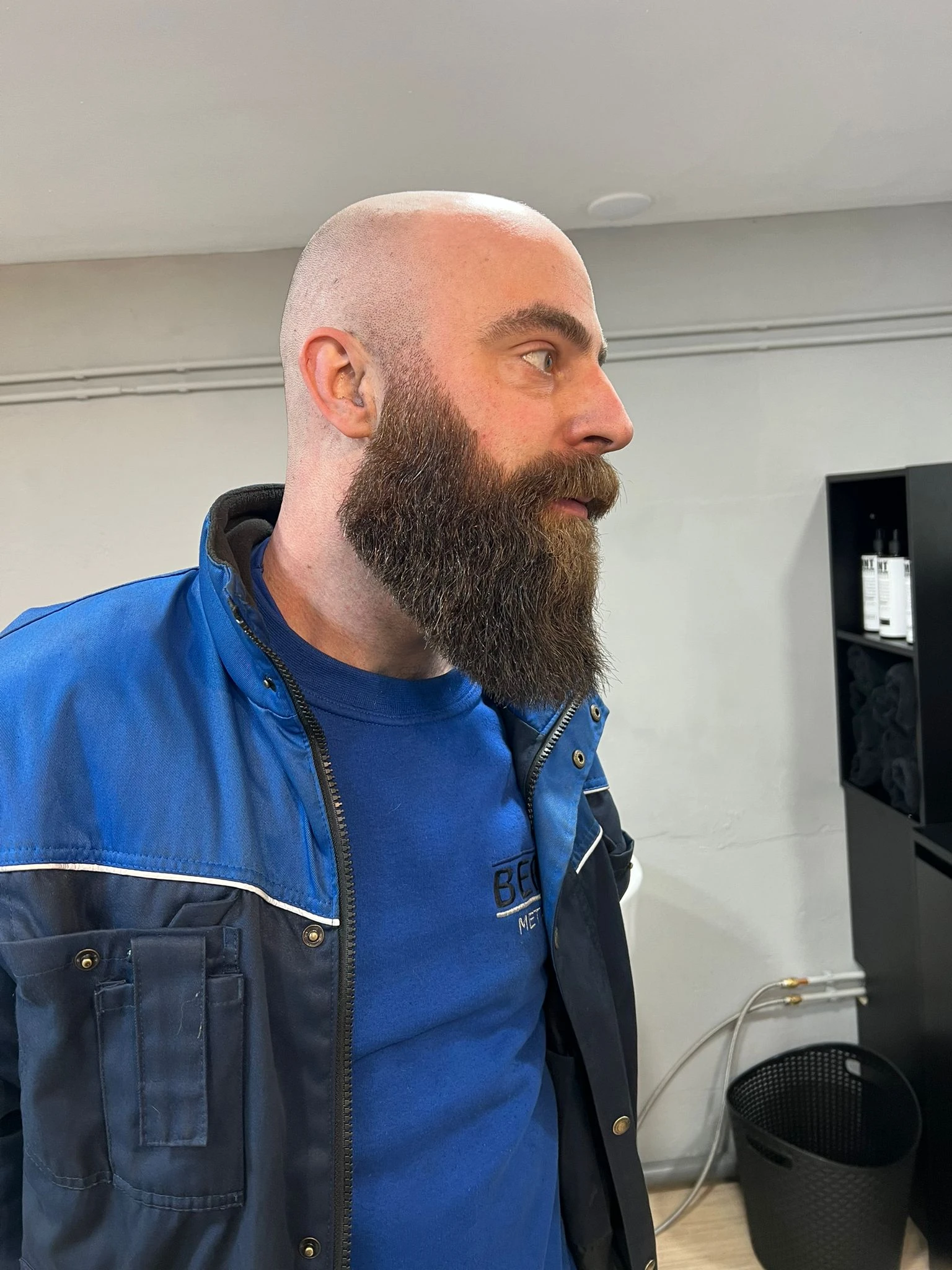 Man met baard in blauw jack in een winkelruimte