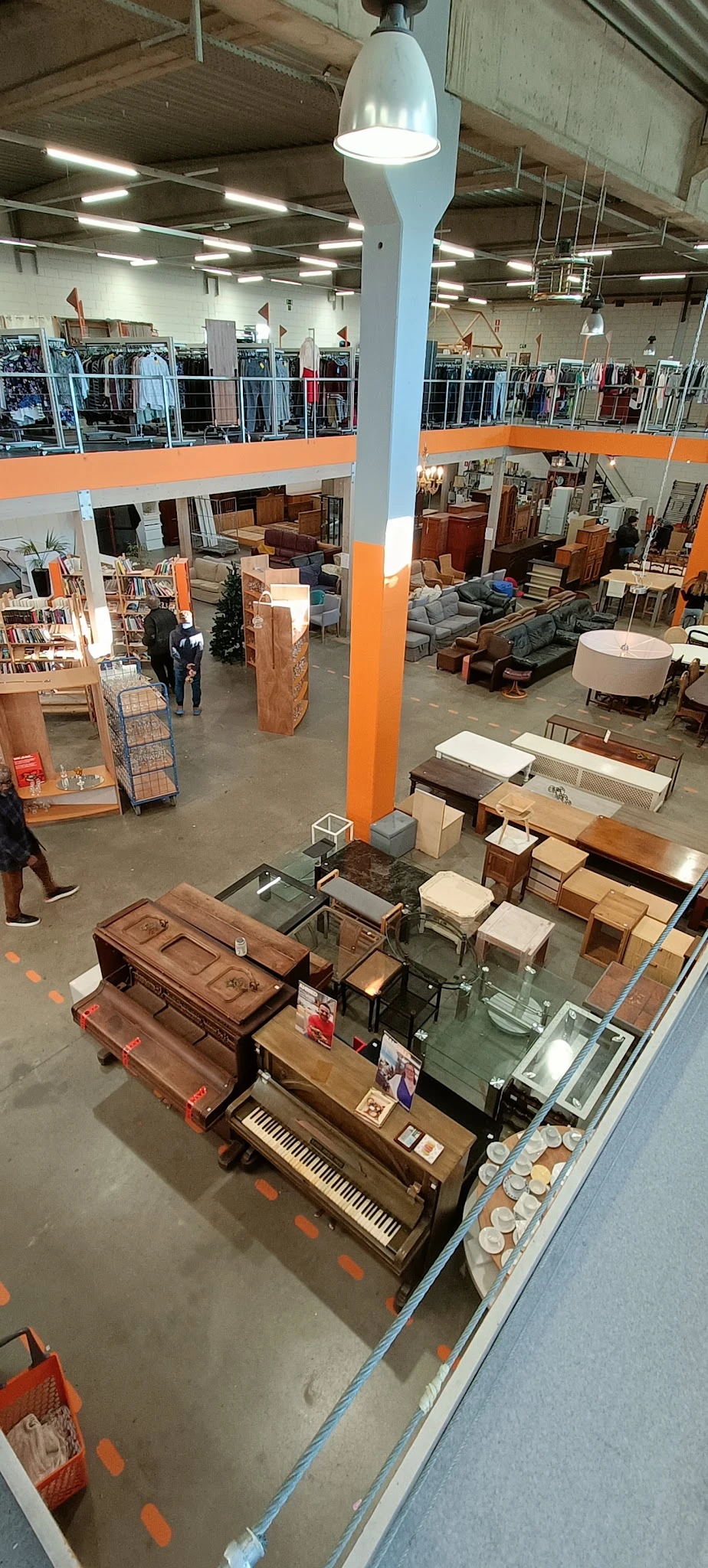 Overzicht van een kringloopwinkel met meubels, tafels, stoelen en huishoudspullen uitgestald op de vloer