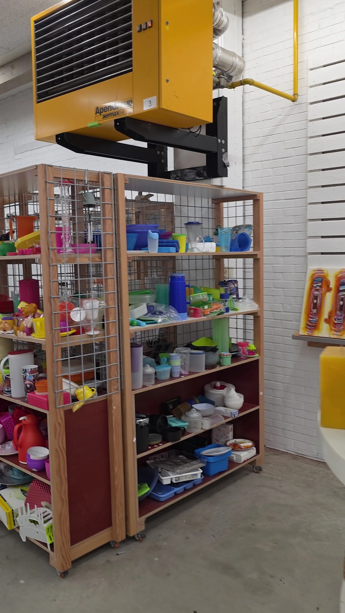 Houten vitrinekast met verscheidene plastic bakken, containers en huishoudartikelen in verschillende kleuren