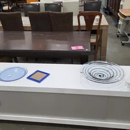 Witte toonbank met huishoudartikelen: blauwe borden, geel dienblad en spiraalvormige items