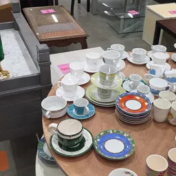 Uitgestalde serviesgoed: kopjes, schotels en borden in verschillende kleuren en patronen op een tafel