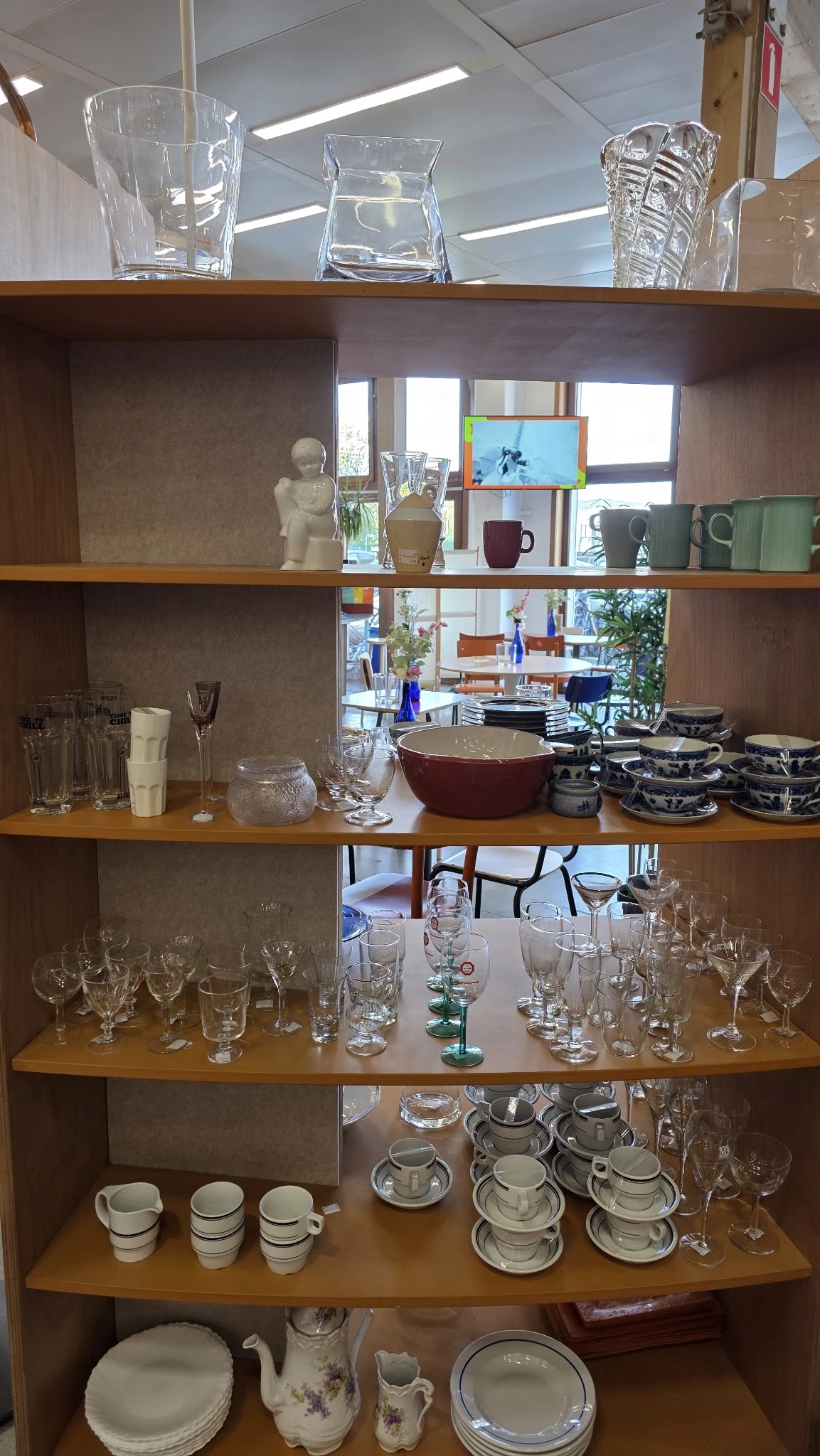 Glazenkast met serviesgoed, glazen en decoratieve items uitgestald op houten planken