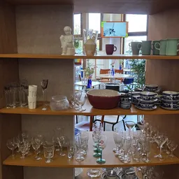 Glazenkast met serviesgoed, glazen en decoratieve items uitgestald op houten planken