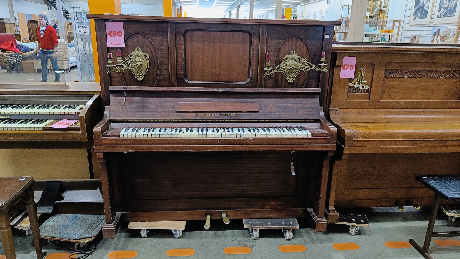 Donkerbruine houten piano met ivoren toetsen en messingwerk in showroom