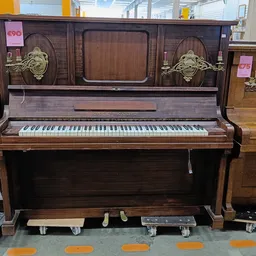 Donkerbruine houten piano met ivoren toetsen en messingwerk in showroom