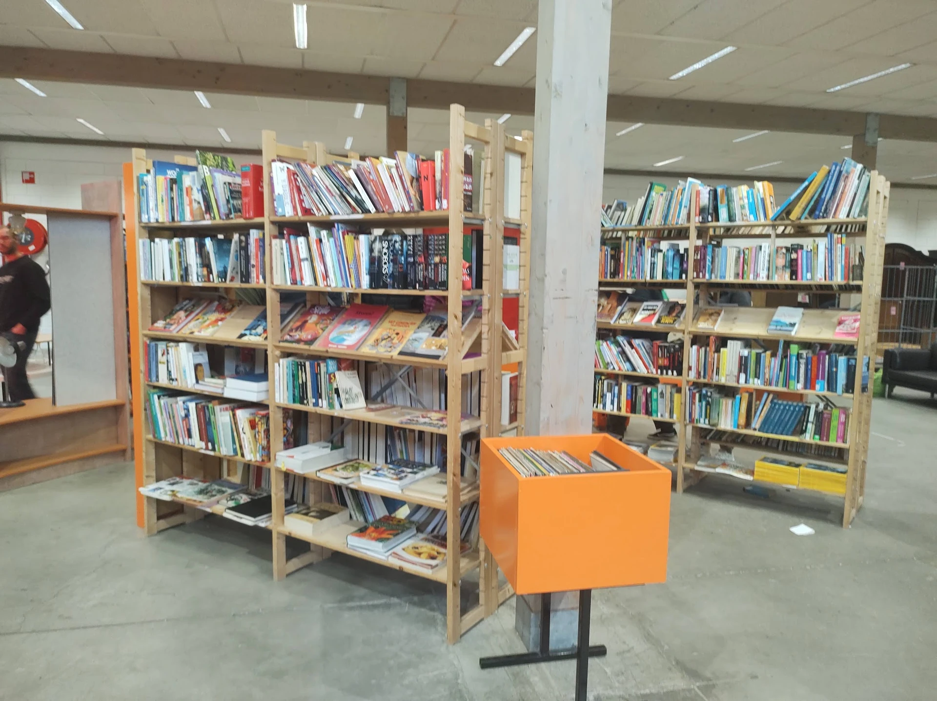 Boekenrekken met tweedehands boeken en een oranje display-element in een winkelruimte