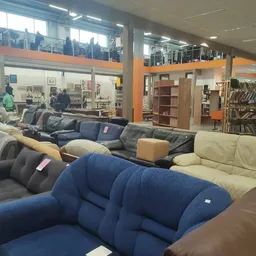 Uitgestalde fauteuils en banken in verschillende kleuren in een kringloopwinkel