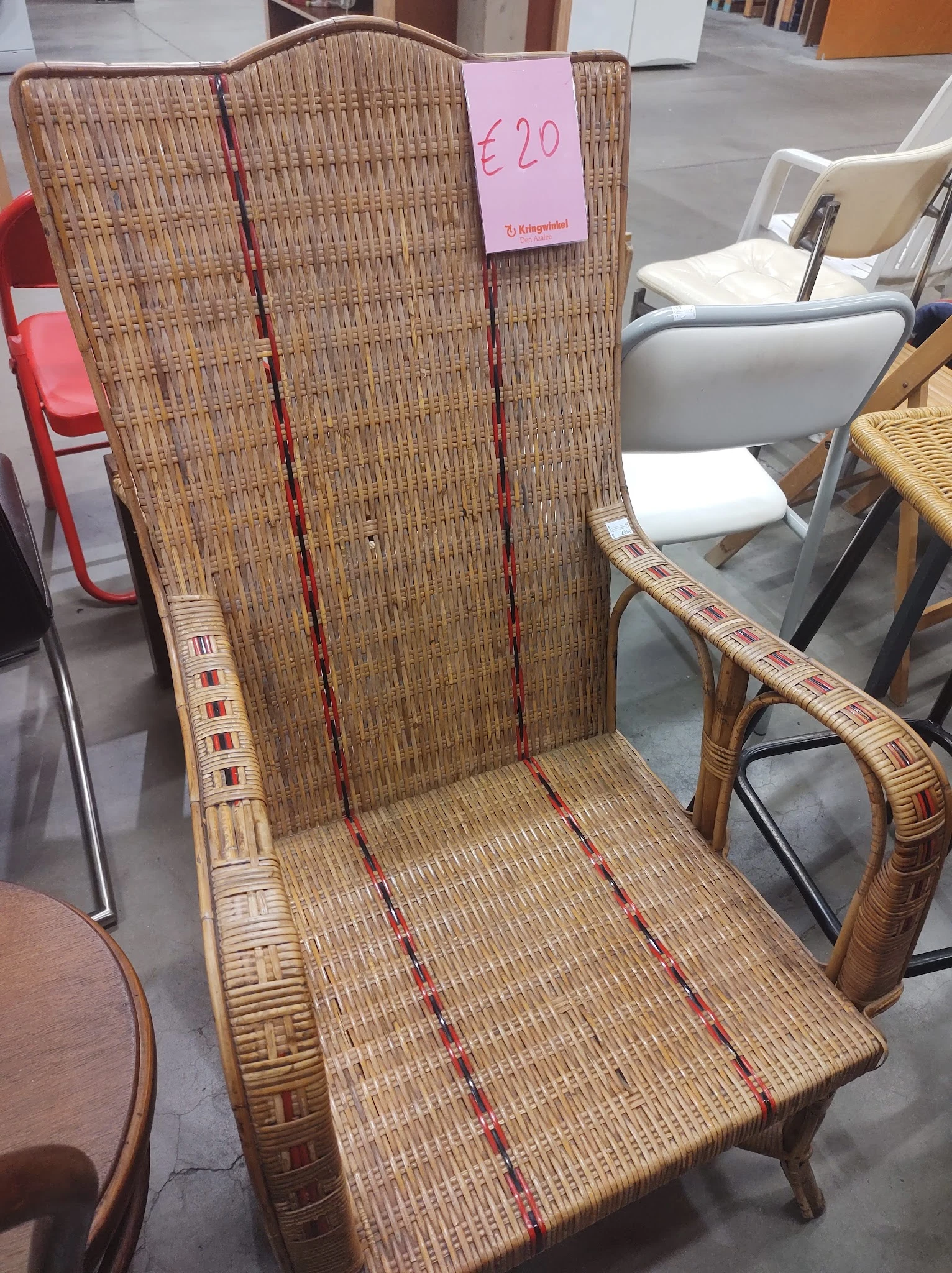 Rotan stoel met rood en crème gestreepte bekleding, gezien van voren in de winkel
