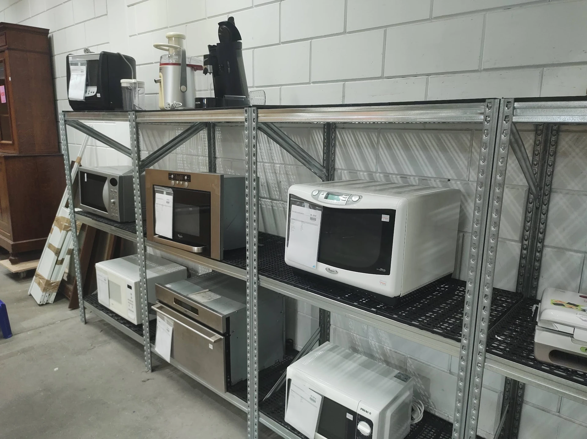 Metalen stellingen met elektrische apparaten: magnetrons, broodroostersm en andere huishoudapparatuur