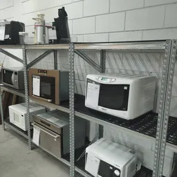Metalen stellingen met elektrische apparaten: magnetrons, broodroostersm en andere huishoudapparatuur