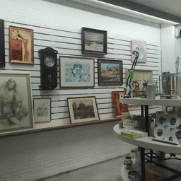 Winkelvloer met slatwall waaraan diverse tweedehands kunstwerken, schilderijen, klokken en decoratieartikelen zijn uitgestald