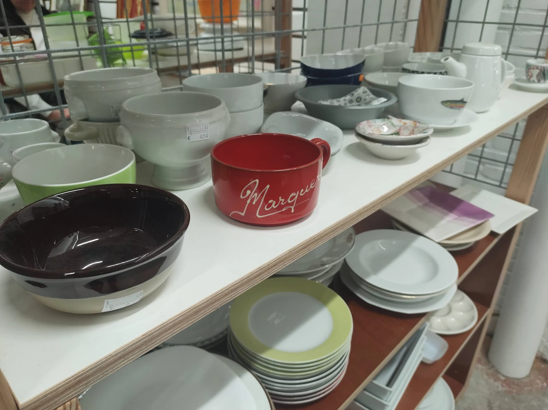 Uitgestalde serviesgoed en schalen in verschillende kleuren op een witte tafel in de winkel