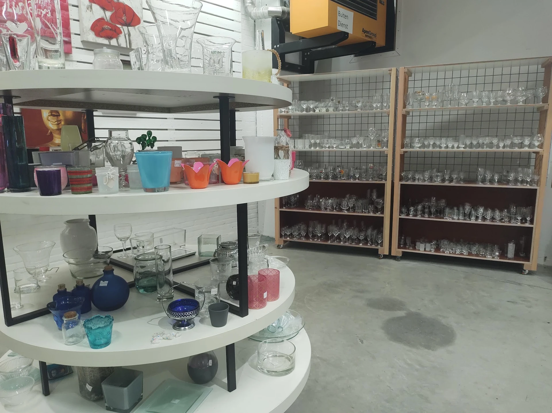 Ronde witte winkelkasten met glazen vitrines vol verzamelobjecten en decoratieve items in een kringloopwinkel
