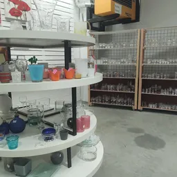 Ronde witte winkelkasten met glazen vitrines vol verzamelobjecten en decoratieve items in een kringloopwinkel